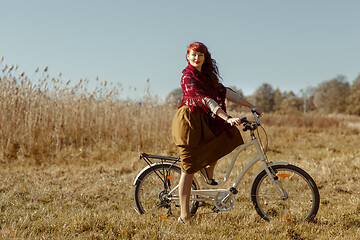 Image showing Pretty girl riding bicycle in field