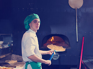 Image showing chef putting delicious pizza to brick wood oven