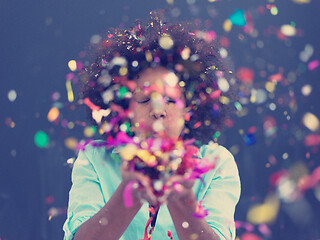 Image showing black woman blowing confetti in the air