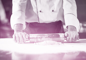 Image showing chef preparing dough for pizza with rolling pin