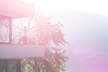 Image showing woman stretching her arms on balcony