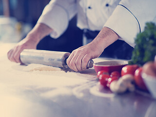 Image showing chef preparing dough for pizza with rolling pin