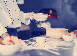 Image showing chef sprinkling flour over fresh pizza dough