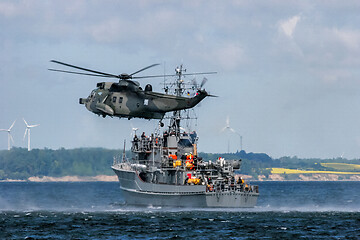 Image showing NATO rescue mission in sea with ship and helicopter.