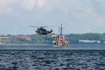 Image showing NATO rescue mission in sea with ship and helicopter.