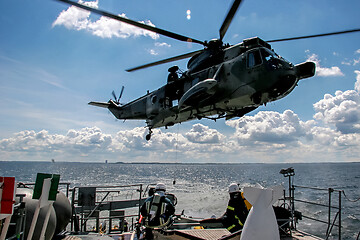 Image showing NATO rescue mission in sea with ship and helicopter.