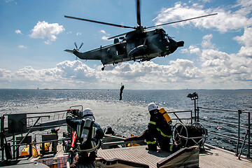 Image showing NATO rescue mission in sea with ship and helicopter.