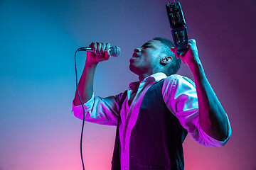 Image showing African American handsome jazz musician playing tambourine and singing.