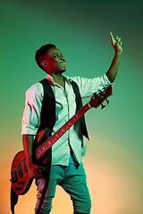 Image showing African American handsome jazz musician holding bass guitar and welcomes the audience.