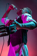 Image showing African American handsome jazz musician playing tambourine and singing.