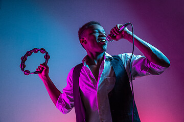 Image showing African American handsome jazz musician playing tambourine and singing.