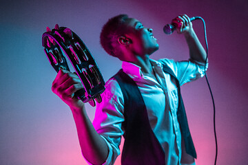 Image showing African American handsome jazz musician playing tambourine and singing.