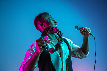 Image showing African American handsome jazz musician playing tambourine and singing.