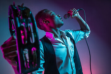 Image showing African American handsome jazz musician playing tambourine and singing.