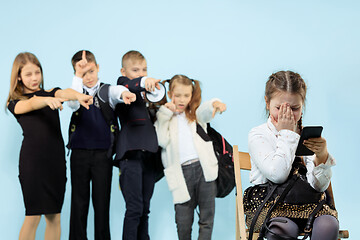 Image showing Little girl sitting alone on chair and suffering an act of bullying.