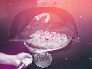 Image showing chef removing hot pizza from stove