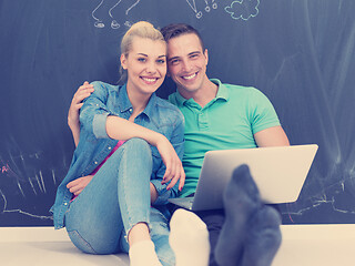 Image showing couple using laptop in front of gray chalkboard