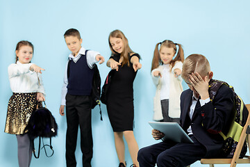 Image showing Little boy sitting alone on chair and suffering an act of bullying.