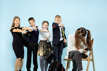 Image showing Little girl sitting alone on chair and suffering an act of bullying.