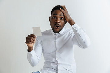 Image showing Young afro man with a surprised happy expression won a bet on gray studio background. Human facial emotions and betting concept.