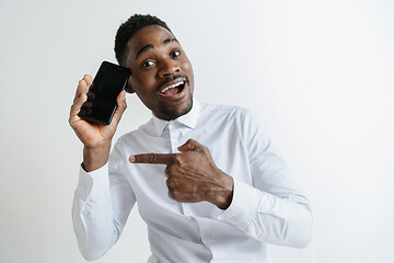 Image showing Indoor portrait of attractive young black african man isolated on pink background, holding blank smartphone, smiling at camera, showing screen, feeling happy and surprised. Human emotions, facial