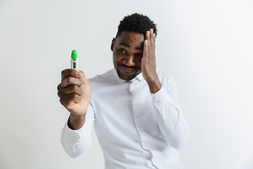 Image showing Young unhappy african american man looking at pregnancy test. Handsome sad man frustrated and having problems. Guy depressed because of result of pregnancy test