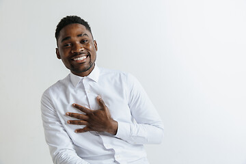 Image showing Grateful happy pleased african man holding hands on chest.