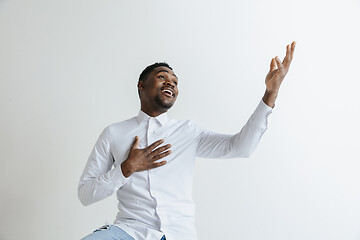 Image showing Grateful happy pleased african man holding hands on chest.