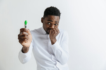 Image showing Young unhappy african american man looking at pregnancy test. Handsome sad man frustrated and having problems. Guy depressed because of result of pregnancy test