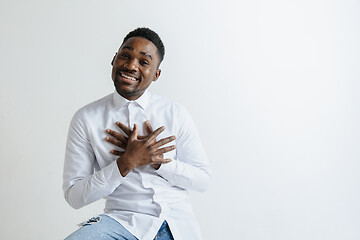 Image showing Grateful happy pleased african man holding hands on chest.