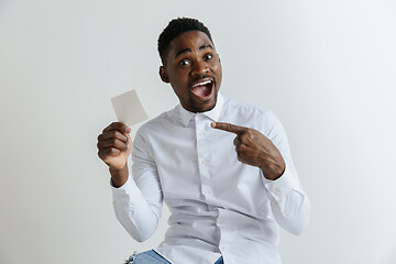 Image showing Young afro man with a surprised happy expression won a bet on gray studio background. Human facial emotions and betting concept.