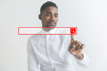 Image showing Young african american guy interacts with empty search bar. Negative space to insert your text.