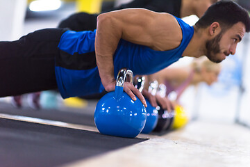 Image showing young athletes doing pushups with kettlebells