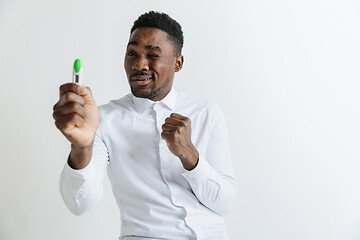 Image showing Young unhappy african american man looking at pregnancy test. Handsome sad man frustrated and having problems. Guy depressed because of result of pregnancy test