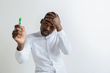 Image showing Young unhappy african american man looking at pregnancy test. Handsome sad man frustrated and having problems. Guy depressed because of result of pregnancy test