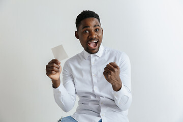 Image showing Young afro man with a surprised happy expression won a bet on gray studio background. Human facial emotions and betting concept.