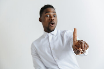 Image showing Young african american guy interacts with empty space. Negative space to insert your text or image.