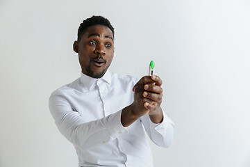 Image showing Young happy african american man looking at pregnancy test. Handsome smiling man inspired and delighted. Guy pleased because of result of pregnancy test.