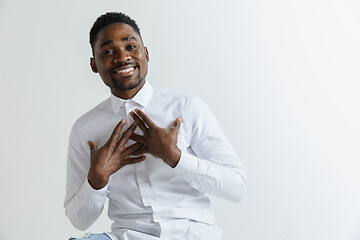 Image showing Grateful happy pleased african man holding hands on chest.