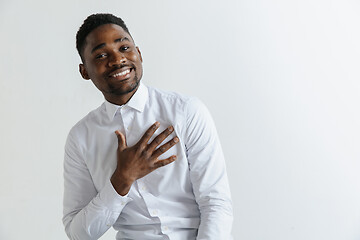 Image showing Grateful happy pleased african man holding hands on chest.