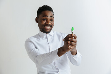 Image showing Young happy african american man looking at pregnancy test. Handsome smiling man inspired and delighted. Guy pleased because of result of pregnancy test.