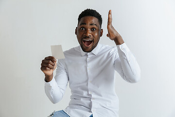 Image showing Young afro man with a surprised happy expression won a bet on gray studio background. Human facial emotions and betting concept.