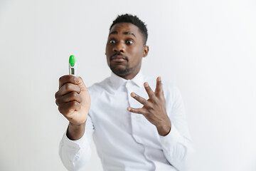 Image showing Young unhappy african american man looking at pregnancy test. Handsome sad man frustrated and having problems. Guy depressed because of result of pregnancy test