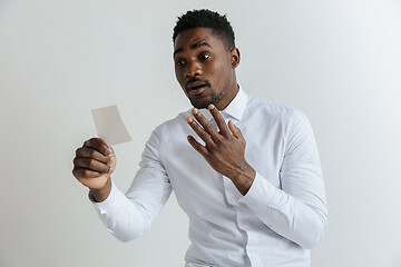 Image showing Young afro man with a disappointed unhappy sad expression lost a bet on gray studio background. Human facial emotions and betting concept.