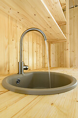 Image showing In a kitchen made of natural wood, water flows from the mixer