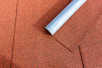 Image showing There is a roll of red bituminous shingles on the tiled roof