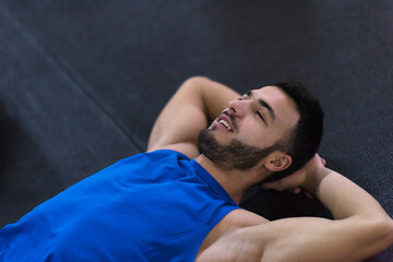 Image showing young athlete man lying on the floor and relaxing