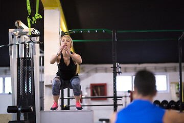 Image showing woman working out with personal trainer jumping on fit box