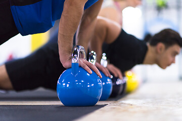 Image showing young athletes doing pushups with kettlebells