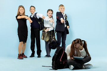 Image showing Little girl sitting alone on floor and suffering an act of bullying.